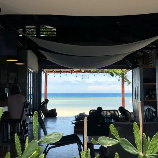 a group of people sitting on a patio by a beach