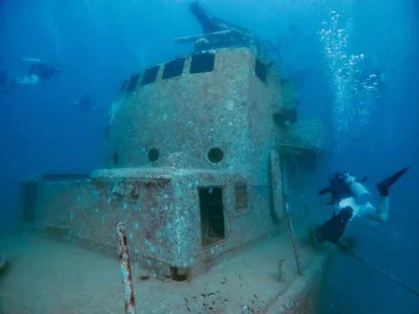 a scuba diver swimming near a shipwreck HTSM 313 Suphairin in Koh Tao