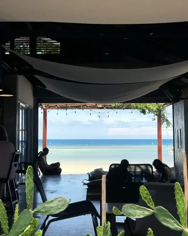 a group of people sitting on a patio by a beach